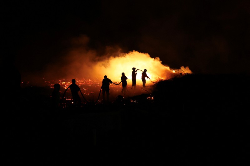 Seorang pria memegang ember selama kebakaran hutan di Nelas, Portugal, 16 September 2024. (REUTERS/Pedro Nunes)