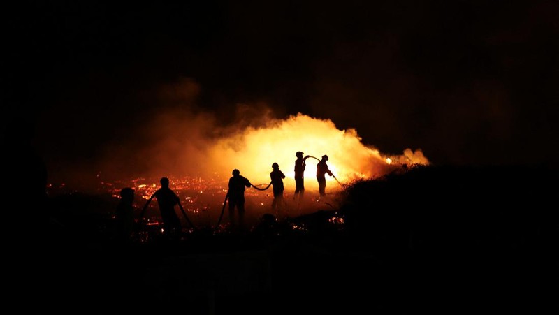 Seorang pria memegang ember selama kebakaran hutan di Nelas, Portugal, 16 September 2024. (REUTERS/Pedro Nunes)