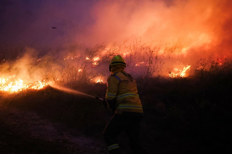Orang-orang meninggalkan rumah mereka saat kebakaran hutan mendekat, di Veiga, Agueda, Portugal, 17 September 2024. (REUTERS/Pedro Nunes)