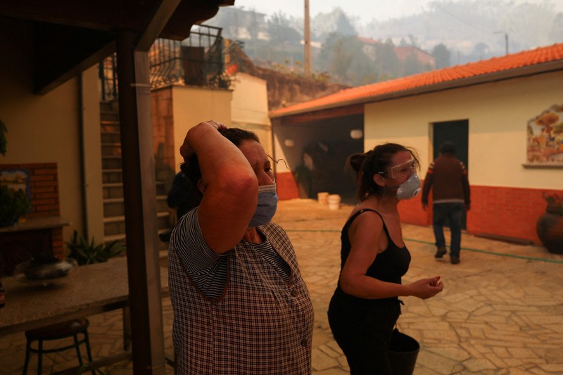 Orang-orang meninggalkan rumah mereka saat kebakaran hutan mendekat, di Veiga, Agueda, Portugal, 17 September 2024. (REUTERS/Pedro Nunes)