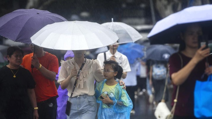 Wisatawan yang membawa payung menjelajahi Danau Barat di tengah hujan yang dibawa oleh Topan Bebinca selama liburan Festival Pertengahan Musim Gugur, di Hangzhou di provinsi Zhejiang, China timur, Senin, 16 September 2024. (Chinatopix Via AP)