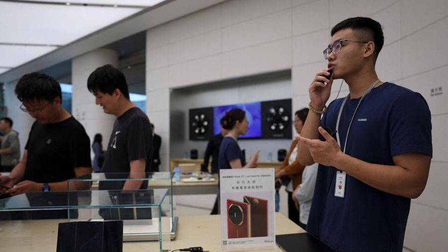 Seorang staf memperkenalkan Huawei Mate XT saat ponsel pintar lipat tiga itu mulai dijual di toko utama Huawei di Beijing, Tiongkok, 20 September 2024. (REUTERS/Florence Lo)