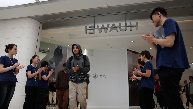 Orang-orang mengantre untuk melihat ponsel utama Huawei pintar lipat tiga Huawei Mate XT mulai dijual di Beijing, Tiongkok, 20 September 2024. (REUTERS/Wang Jiawei)