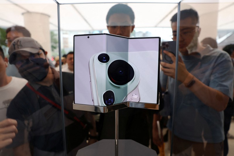 Orang-orang mengantre untuk melihat ponsel utama Huawei pintar lipat tiga Huawei Mate XT mulai dijual di Beijing, Tiongkok, 20 September 2024. (REUTERS/Wang Jiawei)