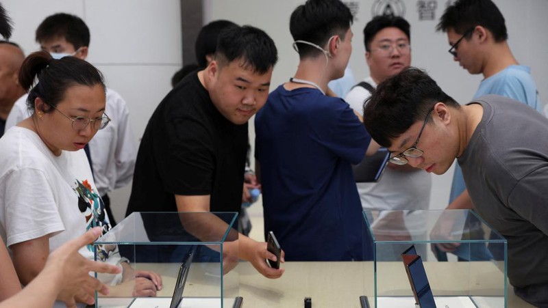 Orang-orang mengantre untuk melihat ponsel utama Huawei pintar lipat tiga Huawei Mate XT mulai dijual di Beijing, Tiongkok, 20 September 2024. (REUTERS/Wang Jiawei)