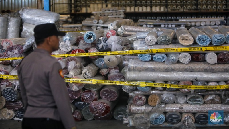 Petugas kepolisian memeriksa barang tekstil dan produk tekstil impor ilegal di Kawasan Industri Jatake, Kota Tangerang, Banten, Senin (23/9/2024). (CNBC Indonesia/Faisal Rahman)