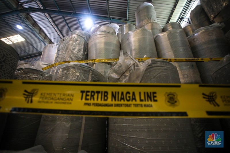 Petugas kepolisian memeriksa barang tekstil dan produk tekstil impor ilegal di Kawasan Industri Jatake, Kota Tangerang, Banten, Senin (23/9/2024). (CNBC Indonesia/Faisal Rahman)