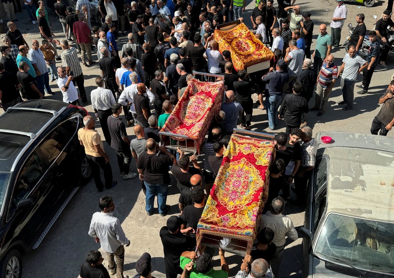 Orang-orang berdiri di atas reruntuhan bangunan yang rusak, di desa Akbiyeh di selatan Lebanon, di tengah permusuhan lintas perbatasan antara Hizbullah dan pasukan Israel, Lebanon, 24 September 2024. (REUTERS/Stringer)
