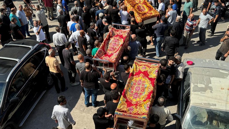 Orang-orang berdiri di atas reruntuhan bangunan yang rusak, di desa Akbiyeh di selatan Lebanon, di tengah permusuhan lintas perbatasan antara Hizbullah dan pasukan Israel, Lebanon, 24 September 2024. (REUTERS/Stringer)