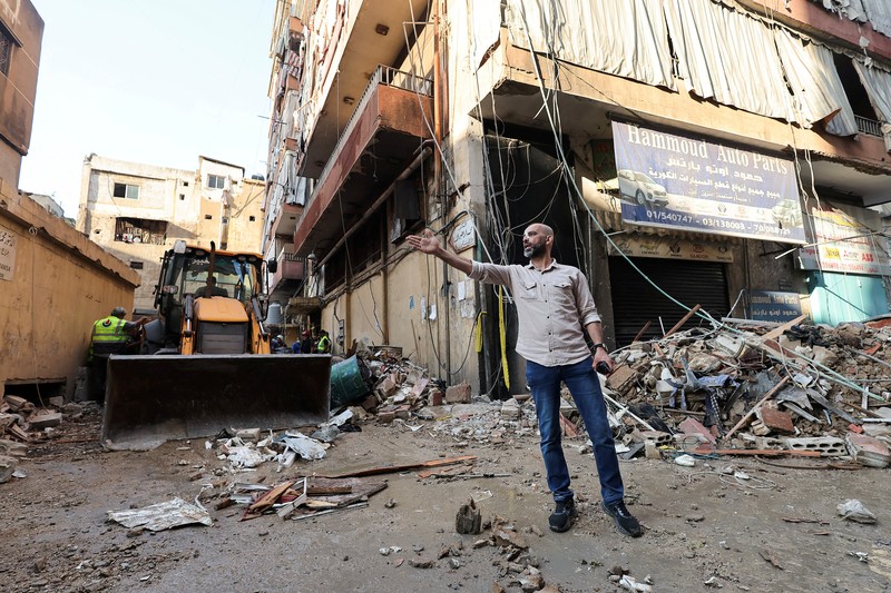 Orang-orang berdiri di atas reruntuhan bangunan yang rusak, di desa Akbiyeh di selatan Lebanon, di tengah permusuhan lintas perbatasan antara Hizbullah dan pasukan Israel, Lebanon, 24 September 2024. (REUTERS/Stringer)