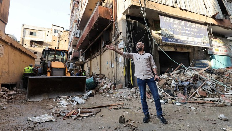 Orang-orang berdiri di atas reruntuhan bangunan yang rusak, di desa Akbiyeh di selatan Lebanon, di tengah permusuhan lintas perbatasan antara Hizbullah dan pasukan Israel, Lebanon, 24 September 2024. (REUTERS/Stringer)