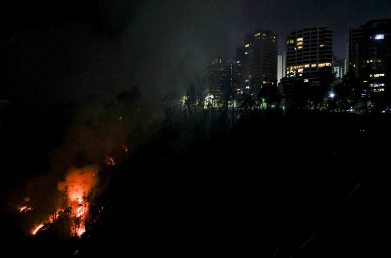 Seorang agen transit mengendarai sepeda motor saat kebakaran hutan melanda, di Quito, Ekuador, 24 September 2024. (REUTERS/Karen Toro)