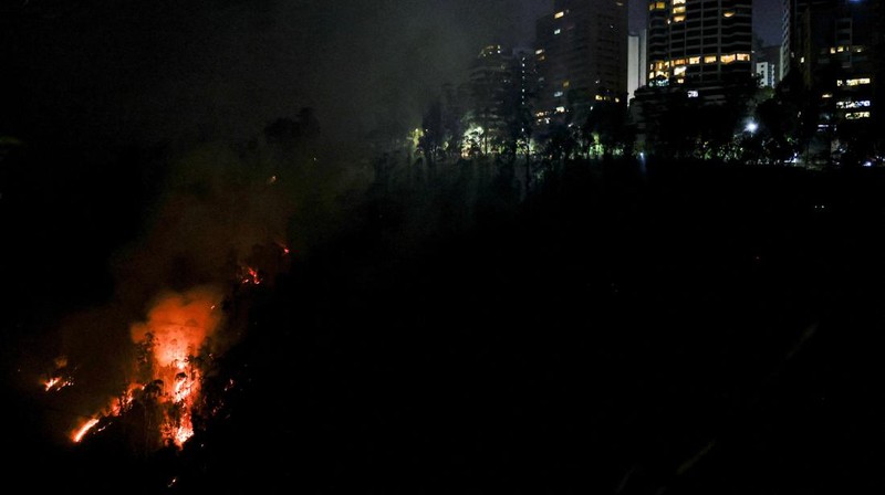 Seorang agen transit mengendarai sepeda motor saat kebakaran hutan melanda, di Quito, Ekuador, 24 September 2024. (REUTERS/Karen Toro)