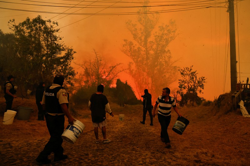 Seorang agen transit mengendarai sepeda motor saat kebakaran hutan melanda, di Quito, Ekuador, 24 September 2024. (REUTERS/Karen Toro)