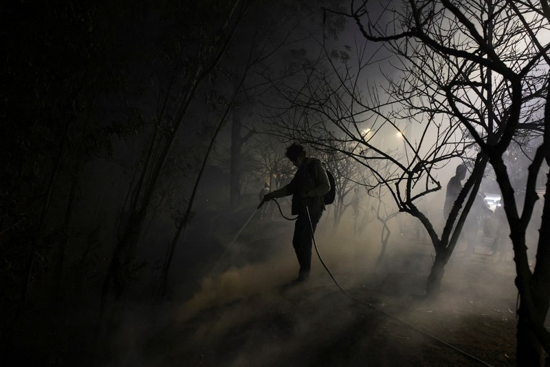 Seorang agen transit mengendarai sepeda motor saat kebakaran hutan melanda, di Quito, Ekuador, 24 September 2024. (REUTERS/Karen Toro)