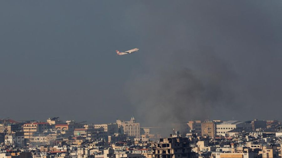 Sebuah pesawat terbang saat asap mengepul di atas pinggiran selatan Beirut, di tengah permusuhan yang sedang berlangsung antara Hizbullah dan pasukan Israel, seperti yang terlihat dari Sin El Fil, Lebanon, 28 September 2024. (REUTERS/Mohamed Azakir)