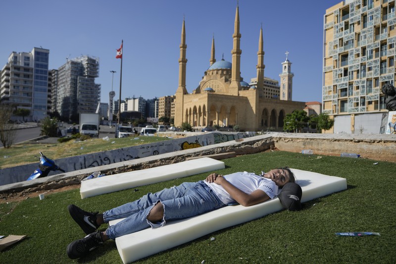 A family sleep on the ground in Beirut's corniche area after fleeing the Israeli airstrikes in the southern suburbs of Dahiyeh, Sunday, Sept. 29, 2024. (AP Photo/Bilal Hussein)