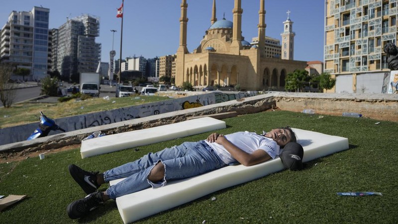 A family sleep on the ground in Beirut's corniche area after fleeing the Israeli airstrikes in the southern suburbs of Dahiyeh, Sunday, Sept. 29, 2024. (AP Photo/Bilal Hussein)