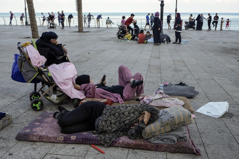 Lebanon Israel A family sleep on the ground in Beirut's corniche area after fleeing the Israeli airstrikes in the southern suburbs of Dahiyeh, Sunday, Sept. 29, 2024. (AP Photo/Bilal Hussein)