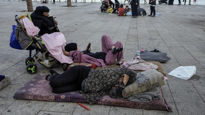 A family sleep on the ground in Beirut's corniche area after fleeing the Israeli airstrikes in the southern suburbs of Dahiyeh, Sunday, Sept. 29, 2024. (AP Photo/Bilal Hussein)