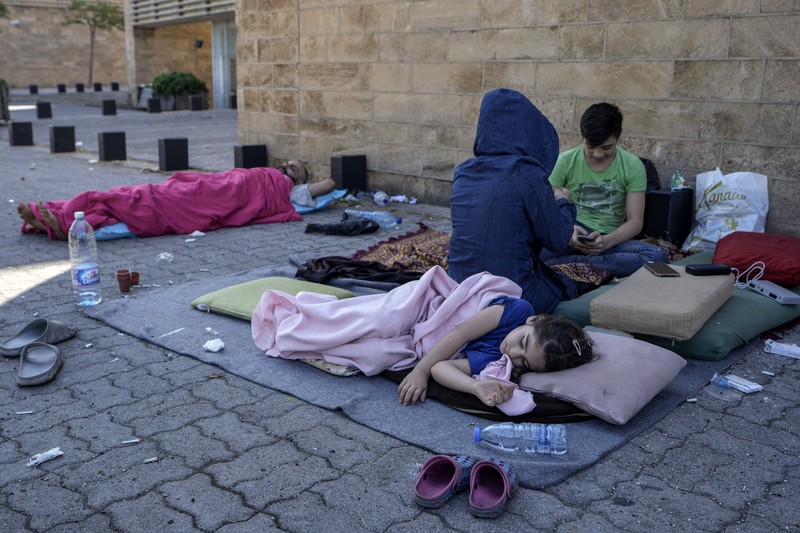 Lebanon Israel A family sleep on the ground in Beirut's corniche area after fleeing the Israeli airstrikes in the southern suburbs of Dahiyeh, Sunday, Sept. 29, 2024. (AP Photo/Bilal Hussein)