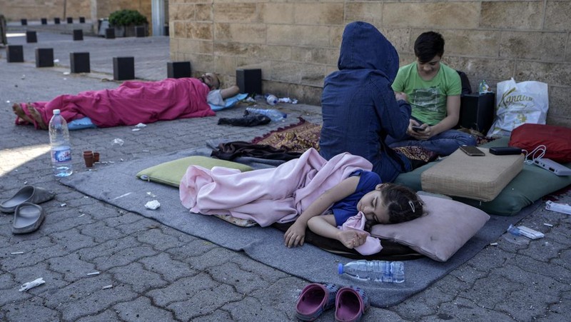 A family sleep on the ground in Beirut's corniche area after fleeing the Israeli airstrikes in the southern suburbs of Dahiyeh, Sunday, Sept. 29, 2024. (AP Photo/Bilal Hussein)