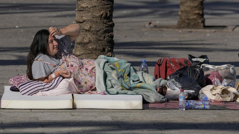 A family sleep on the ground in Beirut's corniche area after fleeing the Israeli airstrikes in the southern suburbs of Dahiyeh, Sunday, Sept. 29, 2024. (AP Photo/Bilal Hussein)