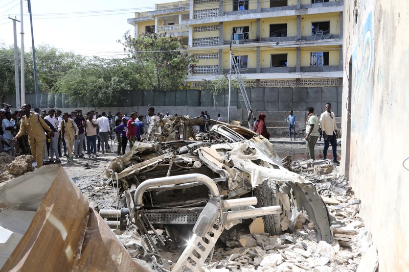 SOMALIA-SECURITY/ Somali security officers guard residents from the wreckage of a car at the scene of an explosion on a bomb-rigged car that was parked on a road near the National Theatre in Hamarweyne district of Mogadishu, Somalia September 28, 2024. REUTERS/Feisal Omar