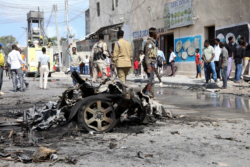 SOMALIA-SECURITY/ Somali security officers guard residents from the wreckage of a car at the scene of an explosion on a bomb-rigged car that was parked on a road near the National Theatre in Hamarweyne district of Mogadishu, Somalia September 28, 2024. REUTERS/Feisal Omar