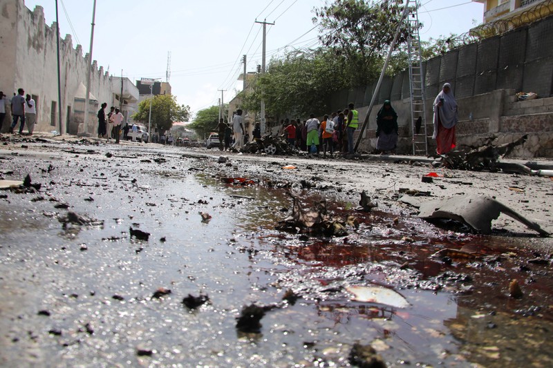 Somali security officers guard residents from the wreckage of a car at the scene of an explosion on a bomb-rigged car that was parked on a road near the National Theatre in Hamarweyne district of Mogadishu, Somalia September 28, 2024. REUTERS/Feisal Omar