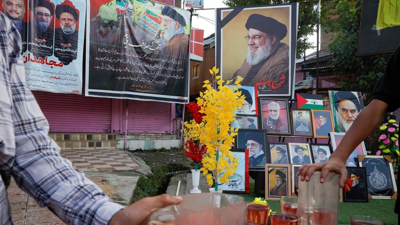 Muslim Syiah Pakistan membawa bendera saat memprotes pembunuhan pemimpin Hizbullah Lebanon Sayyed Hassan Nasrallah dalam serangan udara Israel di Beirut, dengan kontainer pengiriman yang digunakan untuk memblokir area menuju Konsulat AS di Karachi, Pakistan, 29 September 2024. (REUTERS/Imran Ali)