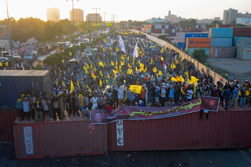 Muslim Syiah Pakistan membawa bendera saat memprotes pembunuhan pemimpin Hizbullah Lebanon Sayyed Hassan Nasrallah dalam serangan udara Israel di Beirut, dengan kontainer pengiriman yang digunakan untuk memblokir area menuju Konsulat AS di Karachi, Pakistan, 29 September 2024. (REUTERS/Imran Ali)