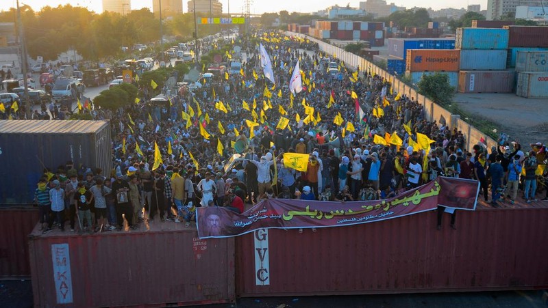 Muslim Syiah Pakistan membawa bendera saat memprotes pembunuhan pemimpin Hizbullah Lebanon Sayyed Hassan Nasrallah dalam serangan udara Israel di Beirut, dengan kontainer pengiriman yang digunakan untuk memblokir area menuju Konsulat AS di Karachi, Pakistan, 29 September 2024. (REUTERS/Imran Ali)