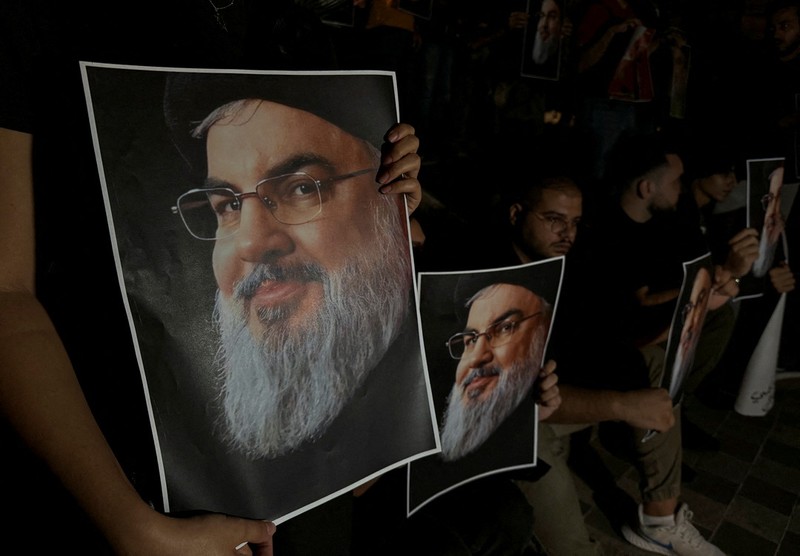 Muslim Syiah Pakistan membawa bendera saat memprotes pembunuhan pemimpin Hizbullah Lebanon Sayyed Hassan Nasrallah dalam serangan udara Israel di Beirut, dengan kontainer pengiriman yang digunakan untuk memblokir area menuju Konsulat AS di Karachi, Pakistan, 29 September 2024. (REUTERS/Imran Ali)