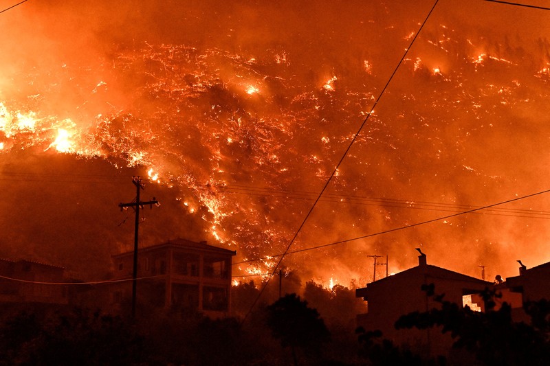 Seorang petugas pemadam kebakaran berusaha memadamkan kebakaran hutan yang terjadi di dekat desa Kallithea, dekat Korintus, Yunani, Senin (30/9/2024). (REUTERS/Vassilis Psomas)