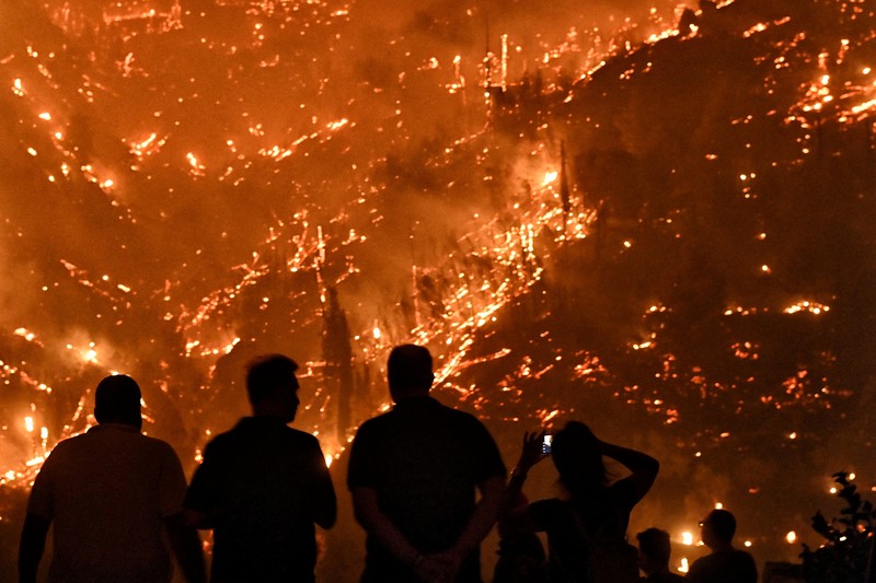 Seorang petugas pemadam kebakaran berusaha memadamkan kebakaran hutan yang terjadi di dekat desa Kallithea, dekat Korintus, Yunani, Senin (30/9/2024). (REUTERS/Vassilis Psomas)