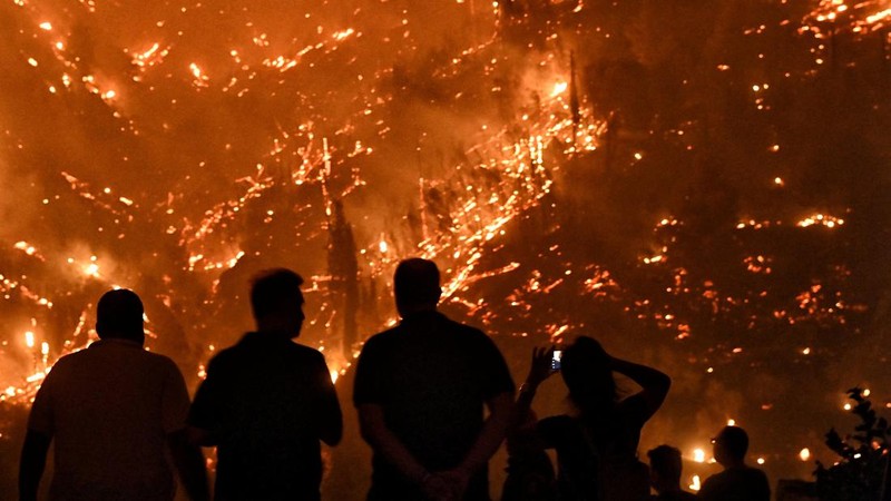 Seorang petugas pemadam kebakaran berusaha memadamkan kebakaran hutan yang terjadi di dekat desa Kallithea, dekat Korintus, Yunani, Senin (30/9/2024). (REUTERS/Vassilis Psomas)