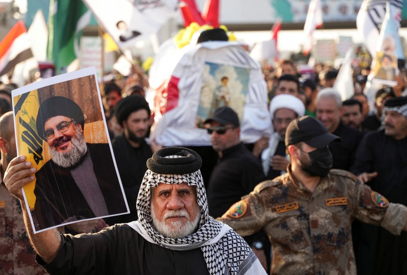 Muslim Syiah Pakistan membawa bendera saat memprotes pembunuhan pemimpin Hizbullah Lebanon Sayyed Hassan Nasrallah dalam serangan udara Israel di Beirut, dengan kontainer pengiriman yang digunakan untuk memblokir area menuju Konsulat AS di Karachi, Pakistan, 29 September 2024. (REUTERS/Imran Ali)