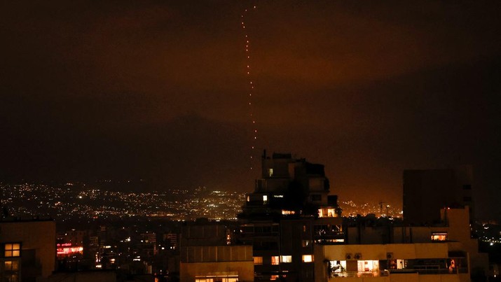 Anggota Komando Front Dalam Negeri Israel dan pasukan polisi memeriksa kawah yang ditinggalkan oleh proyektil yang meledak di gedung sekolah yang rusak parah di kota Gedera, Israel selatan pada 1 Oktober 2024. (REUTERS/Louisa Gouliamaki)