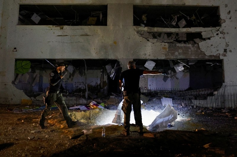 Anggota pasukan penyelamat Israel memeriksa lokasi di mana rudal yang ditembakkan dari Iran ke Israel menghantam gedung sekolah, di Israel tengah, 1 Oktober 2024. (REUTERS/Amir Cohen)