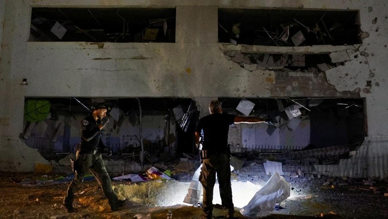 Anggota pasukan penyelamat Israel memeriksa lokasi di mana rudal yang ditembakkan dari Iran ke Israel menghantam gedung sekolah, di Israel tengah, 1 Oktober 2024. (REUTERS/Amir Cohen)