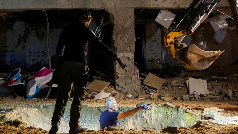 Anggota pasukan penyelamat Israel memeriksa lokasi di mana rudal yang ditembakkan dari Iran ke Israel menghantam gedung sekolah, di Israel tengah, 1 Oktober 2024. (REUTERS/Amir Cohen)