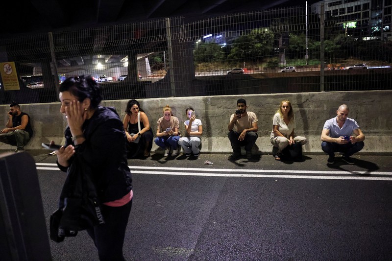 Orang-orang berlari, setelah Iran menembakkan salvo rudal balistik, di tengah permusuhan lintas perbatasan antara Hizbullah dan Israel, dekat Tel Aviv, Israel, 1 Oktober 2024. (REUTERS/Ammar Awad)