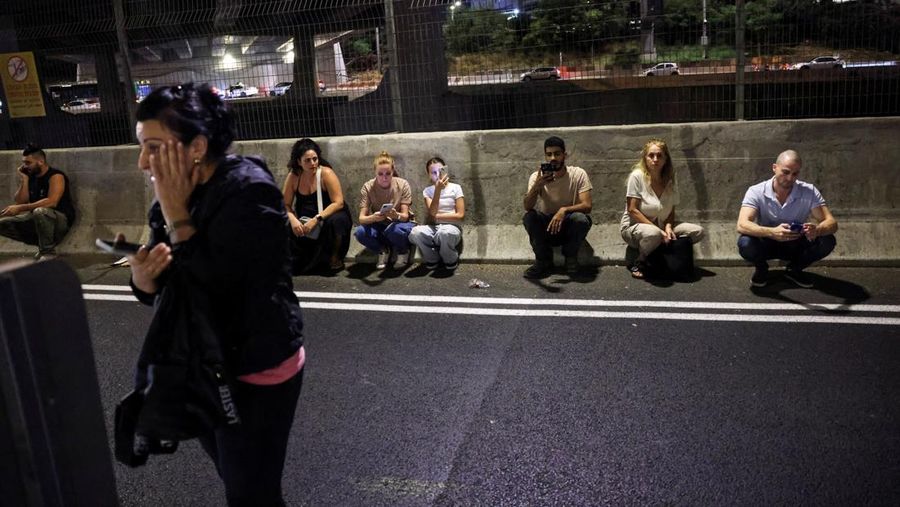 Orang-orang berlindung di pinggir jalan saat sirene berbunyi, setelah Iran menembakkan salvo rudal balistik ke Israel, di Tel Aviv, Israel, 1 Oktober 2024. (REUTERS/Tomer Appelbaum)
ISRAEL OUT. NO COMMERCIAL OR EDITORIAL SALES IN ISRAEL