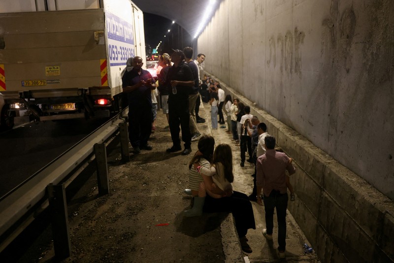 Orang-orang berlari, setelah Iran menembakkan salvo rudal balistik, di tengah permusuhan lintas perbatasan antara Hizbullah dan Israel, dekat Tel Aviv, Israel, 1 Oktober 2024. (REUTERS/Ammar Awad)