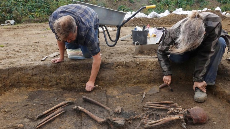 Para arkeolog menggali kerangka di sebuah lubang di situs pemakaman zaman Viking di desa Aasum, Denmark, 25 September 2024. (REUTERS/Tom Little)