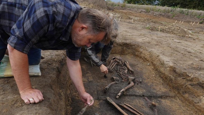 Para arkeolog menggali kerangka di sebuah lubang di situs pemakaman zaman Viking di desa Aasum, Denmark, 25 September 2024. (REUTERS/Tom Little)