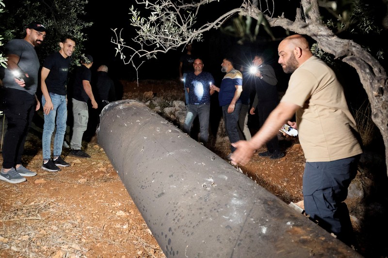 Warga Palestina menyelidiki proyektil, setelah Iran menembakkan salvo rudal balistik, di Tubas, di Tepi Barat yang diduduki Israel, 1 Oktober 2024. (REUTERS/Raneen Sawafta)