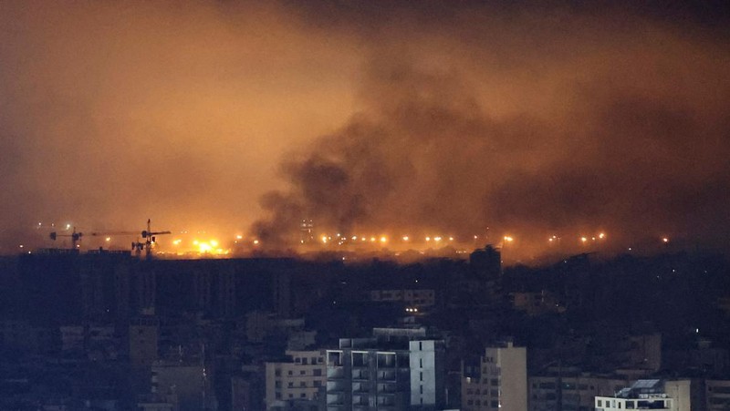 Api dan asap mengepul dari sebuah gedung yang terkena serangan udara Israel di Dahiyeh, sementara Bandara Internasional Rafik Hariri terlihat di latar belakang, di Beirut, Lebanon, Jumat, 4 Oktober 2024. (AP Photo/Hussein Malla)