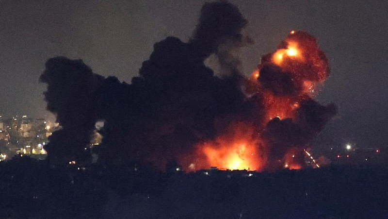 Api dan asap mengepul dari sebuah gedung yang terkena serangan udara Israel di Dahiyeh, sementara Bandara Internasional Rafik Hariri terlihat di latar belakang, di Beirut, Lebanon, Jumat, 4 Oktober 2024. (AP Photo/Hussein Malla)